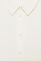 Camisa celeste de manga larga con cuello solapa y pliegues en los puños. Presenta cierre frontal con botones forrados al tono y bajo asimétrico.