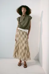 Falda midi de tiro alto, con estampado de cuadros en tonos beige y marrón, costuras marcadas y cierre lateral con cremallera oculta.