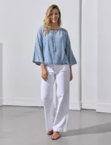 Blusa celeste de lyocell con cuello a la base y escote en V con lazo de ajuste. Manga larga amplia.