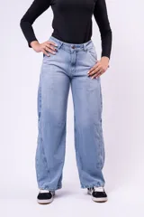 Jean de corte baggy con tiro medio, diseño de pierna ancha y costuras laterales decorativas. Presenta un lavado claro con efecto desgastado.