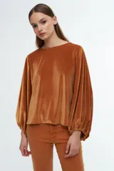 Blusa de terciopelo gris con acabado brillante, cuello redondo y mangas largas abullonadas con puños elásticos.