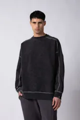 Buzo de cuello redondo con calce oversize, confeccionado en frisa de algodón con efecto de lavado gastado. Presenta costuras a contratono visibles y diseño de recortes en los hombros y mangas.