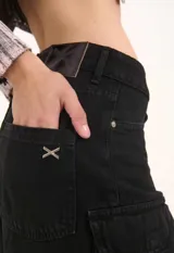 Bermuda de tiro medio confeccionada en denim negro, con calce relajado y estilo cargo. Presenta bolsillos laterales con solapa y terminación desflecada en el ruedo.