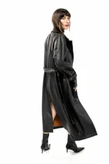 Trench largo de cuero negro con diseño cruzado, solapas amplias, bolsillos laterales y costuras en tono tostado envejecido.