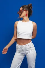 Pantalón de corte recto y tiro medio/alto, confeccionado en gabardina de algodón. Presenta bolsillos delanteros y traseros estilo jean, con costuras de pespunte en color rojo que contrastan con el tejido blanco.