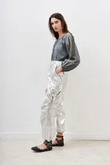 Pantalón cargo de poliamida plateado con efecto metalizado y acabado arrugado. Presenta cintura ajustable con lazo y puños ajustables en los tobillos.