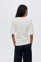 Remera de punto suave de algodón con cuello redondo y detalle de nudo girado en un lateral.
