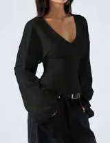 Blusa negra de calce entallado con escote en V y mangas largas amplias tipo campana. Confeccionada en tela suave y liviana con caída fluida.