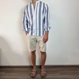 Camisa celeste y blanca a rayas verticales, de lino, con cuello mao y mangas largas con puños.