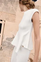 Top blanco de piqué con cuello redondo y mangas cortas, de corte entallado en la cintura y bajo redondeado con acabado en peplum.