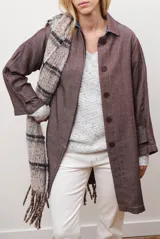 Spolverino largo de jean color azul, con cuello camisero, botones frontales y costuras decorativas en blanco.