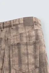 Jeans de corte holgado y amplio en toda la pierna, tiro medio. Tejido rígido con estampado a cuadros con efecto lavado. Cuenta con cinco bolsillos y cierre frontal con cremallera y botón.