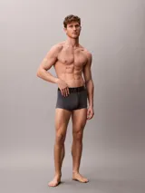 Pack de tres bóxers ajustados Calvin Klein de talle medio, confeccionados en mezcla de algodón y elastano. Incluye una unidad gris melange, una blanca y una azul, todas con cinturilla elástica negra distintiva de la marca.