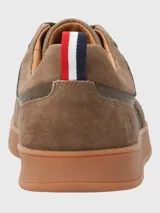 Sneaker de hombre en tonos marrones, confeccionada en una combinación de cuero y descarne. Presenta un diseño de paneles con cordones al tono, suela de goma color caramelo y un detalle de cinta tricolor en el talón.