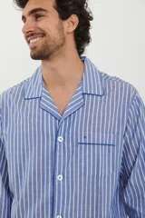Pijama para hombre de camisa manga larga con botones y pantalón largo, ambos a rayas verticales celestes y blancas con ribetes azul marino.