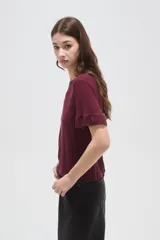Remera negra de viscosa con textura acanalada, cuello redondo y mangas cortas terminadas en volados.