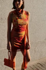 Vestido corto de microtul en doble capa con diseño de rayas diagonales en color rojo y blanco, de corte ajustado al cuerpo, sin mangas, con cuello redondo y detalle drapeado en la cintura.