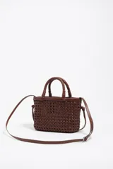 Minibolso marrón de Bimba y Lola, confeccionado en piel vacuna con diseño trenzado y estructura rígida. Cuenta con asas de mano trenzadas, correa de hombro ajustable y etiqueta frontal con el logo de la marca.