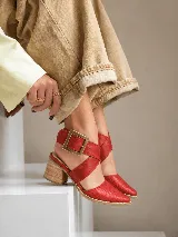 Zapatos de cuero color rojo con textura de cocodrilo, punta fina, tiras cruzadas en el empeine con hebilla metálica grande y taco ancho de madera.