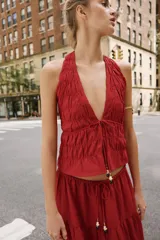 Falda midi color rojo oscuro con diseño de paneles fruncidos, cintura elástica con cordón ajustable y abalorios decorativos.