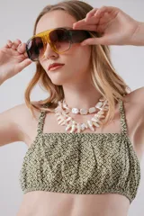 Top tipo bandeau estampado en tonos verde y blanco. Terminaciones y breteles con elástico.