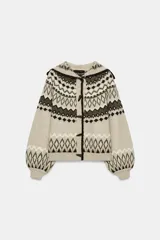 Chaqueta de punto con diseño jacquard de estilo nórdico, en tonos beige, marrón y blanco. Presenta capucha, cierre frontal con botones tipo trenca y mangas largas con puños ajustados.