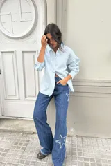 Pantalón de jean azul de corte acampanado con estrellas bordadas en los laterales y terminación desflecada.