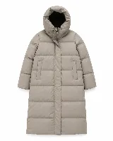 Campera puffer larga de corte recto y silueta envolvente, color beige. Presenta capucha integrada, cierre frontal oculto por solapa y bolsillos laterales. Diseño acolchado con acabado limpio.