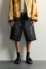 Bermuda de denim de algodón con efecto lavado desgastado en tonos marrones y azules. Tiene tiro medio, diseño de cinco bolsillos, pierna recta de corte holgado y bajo con acabado irregular. Cuenta con cierre frontal de cremallera y botón metálico.
