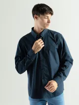 Camisa de manga larga color azul marino, confeccionada en algodón, con cuello abotonado (button-down) y un pequeño logo bordado en el pecho.