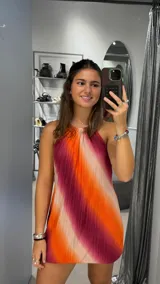 Vestido corto de estilo halter con diseño plisado y estampado de rayas diagonales en tonos naranja, fucsia y beige.