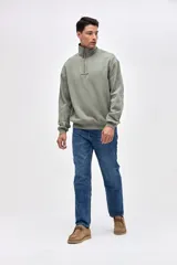 Buzo de felpa con friza, color negro, con cuello alto y cierre frontal parcial. Presenta bordado de la marca en el pecho y un calce relajado.