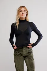 Remera de punto fino semitransparente, color negro, de calce ajustado, con cuello alto, mangas largas y orificios para los pulgares en los puños.