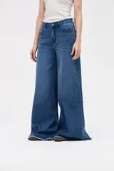 Jean de tiro medio con corte wide leg y diseño de pierna extra ancha. Presenta un lavado azul profundo y ruedo deshilachado.