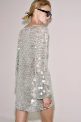 Vestido corto de punto con cuello redondo y manga larga, completamente cubierto de lentejuelas brillantes y perlas decorativas.