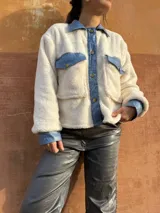 Chaqueta color crema de corderito con detalles en jean azul en cuello, solapa, bolsillos y puños.