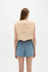 Chaleco sin mangas de algodón con diseño acolchado capitoneado en la parte superior y detalles bordados florales en la parte inferior, con cierre frontal de botones.