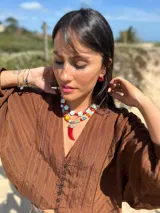 Collar corto con cuentas de flor de cerámica color celeste y cuentas rojas reconstituidas. Se cierra con cadena de acero quirúrgico y ganchito para regular el largo.