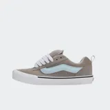 Championes Vans modelo Knu Skool de corte bajo, con diseño robusto inspirado en los años 90. Presentan capellada de gamuza gris, lengüeta y cuello acolchados, cordones anchos blancos y la icónica Sidestripe 3D en color celeste. Incluyen suela vulcanizada blanca con diseño waffle.