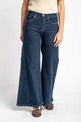 Jean de corte wide leg y tiro medio, confeccionado en denim de algodón. Presenta costuras verticales decorativas a lo largo de las piernas y cierre frontal con botón y cremallera.