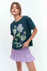 Remera verde oscuro con estampado de flores en tonos verde claro y lila.