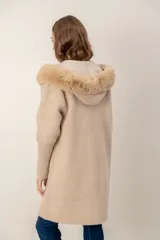 Tapado largo de textura combinada, con cuerpo de punto suave y mangas y bolsillos de tejido tipo corderito. Presenta cuello con capucha de piel sintética y cierre frontal con botones.