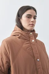 Campera puffer negra con diseño acolchado, capucha integrada y cierre frontal con botones a presión. Presenta puños elásticos y costuras decorativas en el frente.