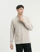 Remera de punto canalé francés con cuello polo, manga larga y cierre frontal de metal con tirador personalizado.