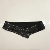 Cinto faja ancho de cuero genuino color negro, con diseño asimétrico y detalle de tachas metálicas plateadas en todo el borde. Cuenta con cierre mediante hebilla metálica ajustable.