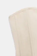 Top tipo corset de escote corazón y hombros descubiertos, con varillas interiores para estructura. Presenta cierre frontal con ganchos metálicos y ajuste en la espalda mediante cordones cruzados.