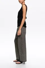 Pantalón tobillero de corte barrel color gris, confeccionado en mezcla de algodón y lino. Presenta cierre frontal con corchete oculto y cremallera, tiro medio, bolsillos delanteros en costura y bolsillos tipo plastrón en la parte trasera.