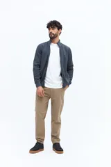 Campera tipo rompevientos o sudadera de algodón, color azul oscuro o gris pizarra, con cuello alto y cierre frontal. Presenta un pequeño logo bordado en el pecho.