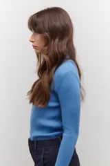 Polera de tejido morley color azul, con cuello alto y mangas largas, de corte ajustado al cuerpo.