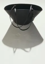 Bolso tipo shopper de tamaño mediano confeccionado en tejido de fibra natural con detalles en poliuretano. Cuenta con dos asas largas para llevar al hombro, cierre de cremallera superior, bolsillo interior y un charm colgante decorativo con herrajes dorados.
